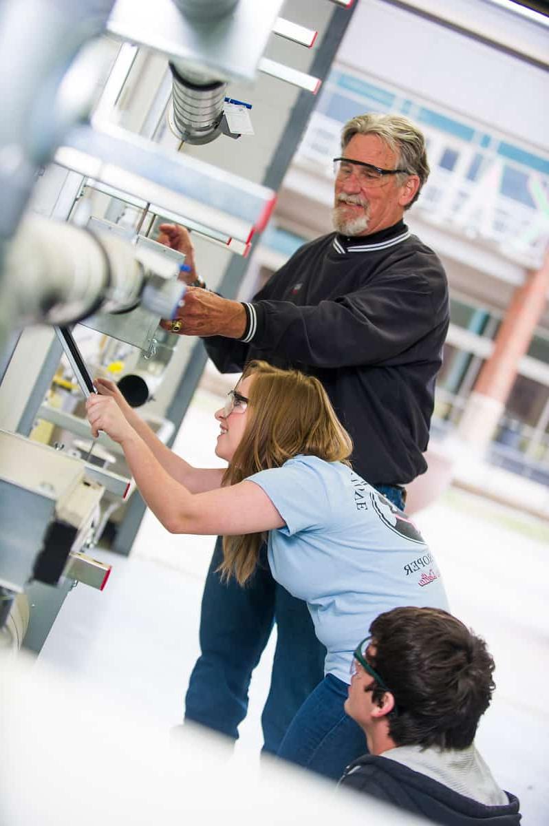 Engineering professor helping students with equipment