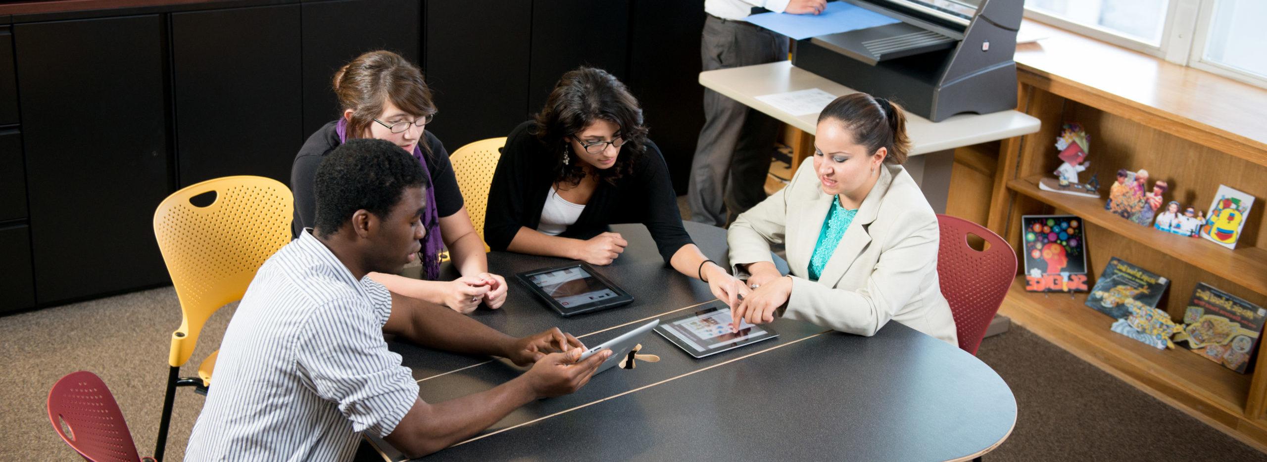 Group of students around table using tablets