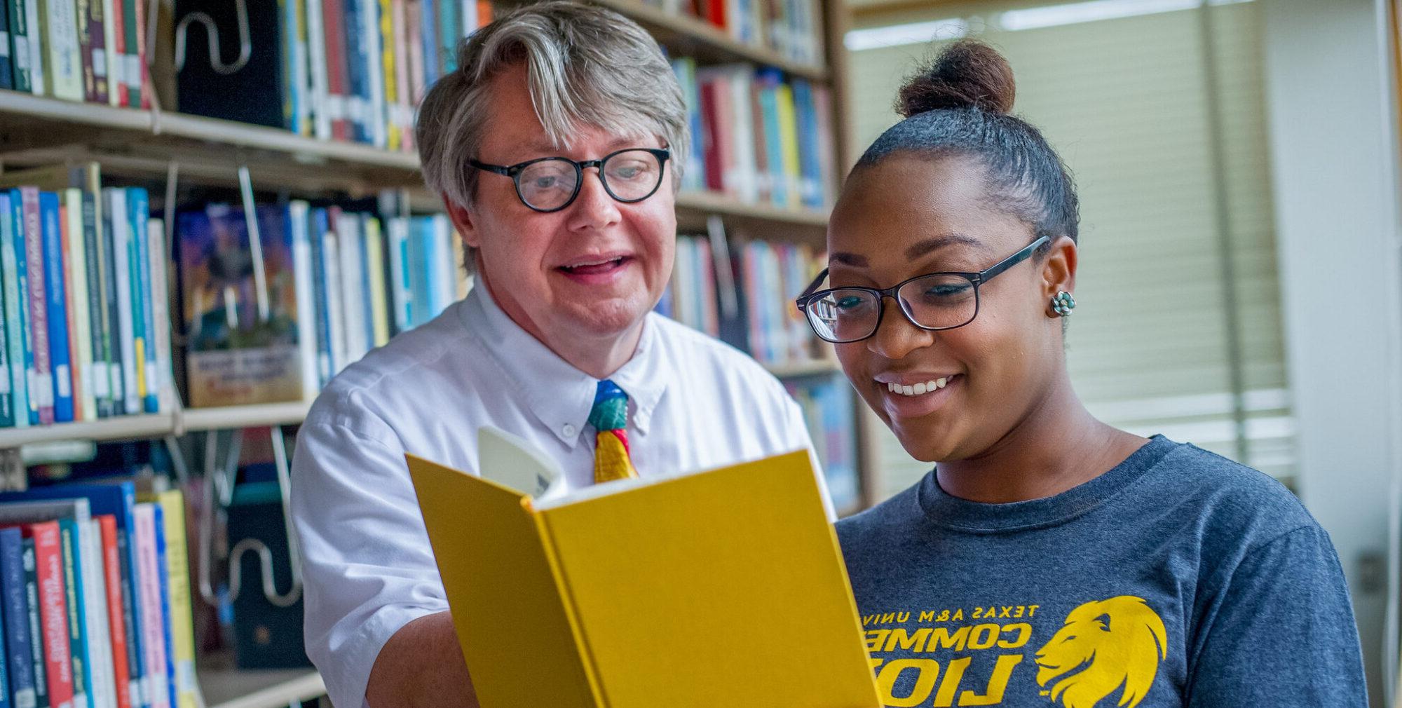 woman and man looking at big yellow book.