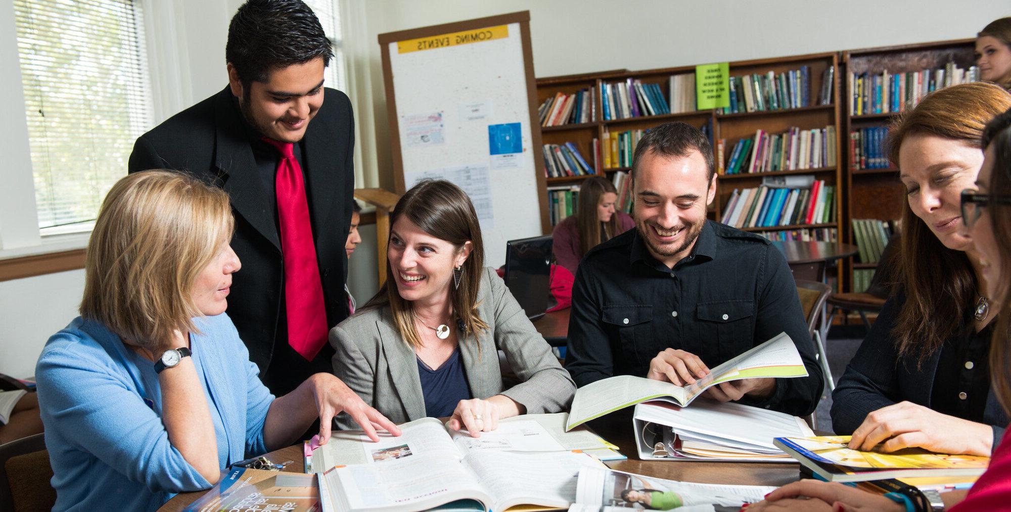 Group of students around a table studying Spanish books.