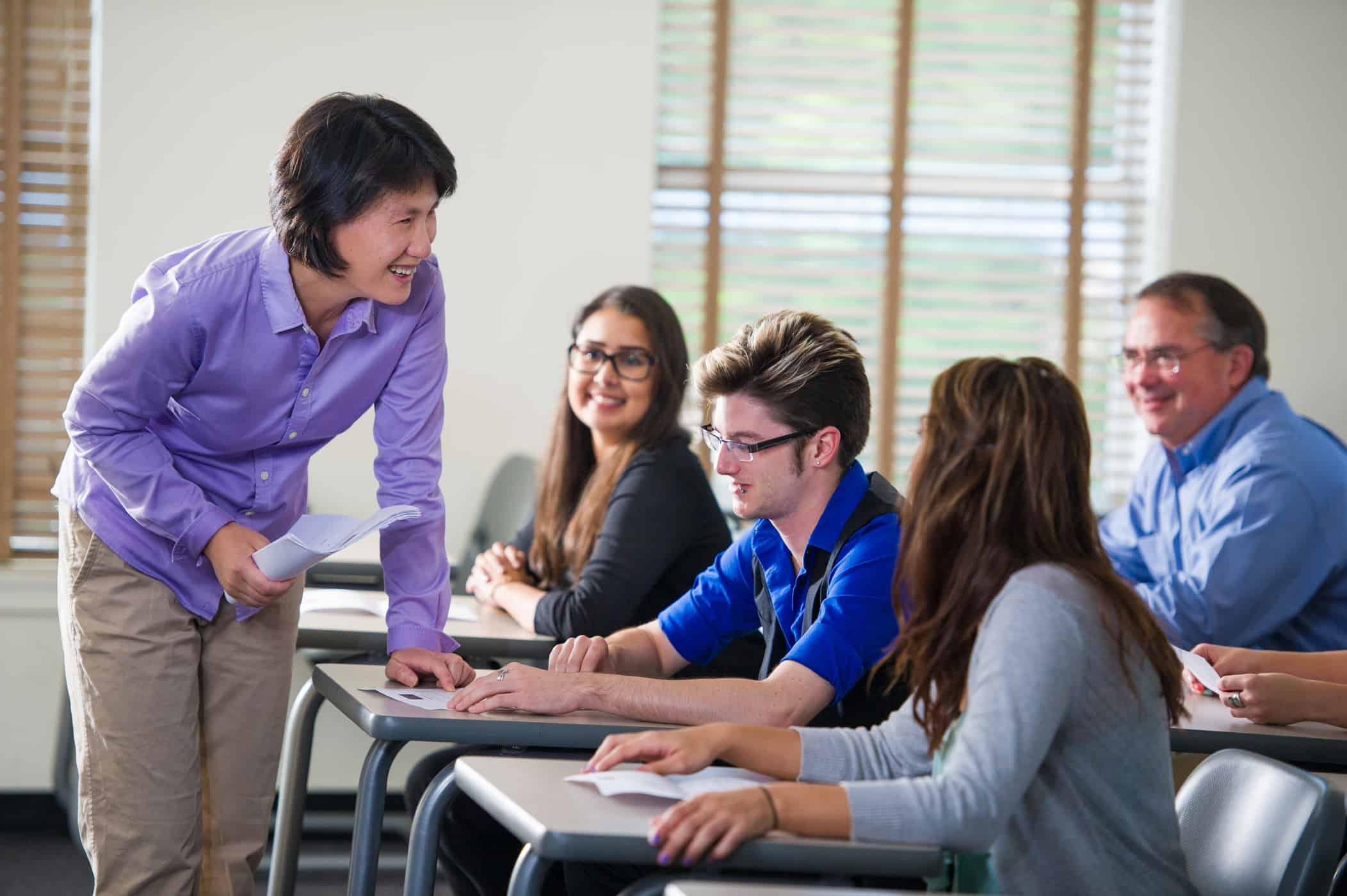 A professor interacting with students in a classroom.