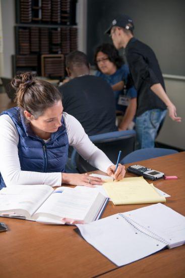 A female student completing school work on a desk in a classroom.