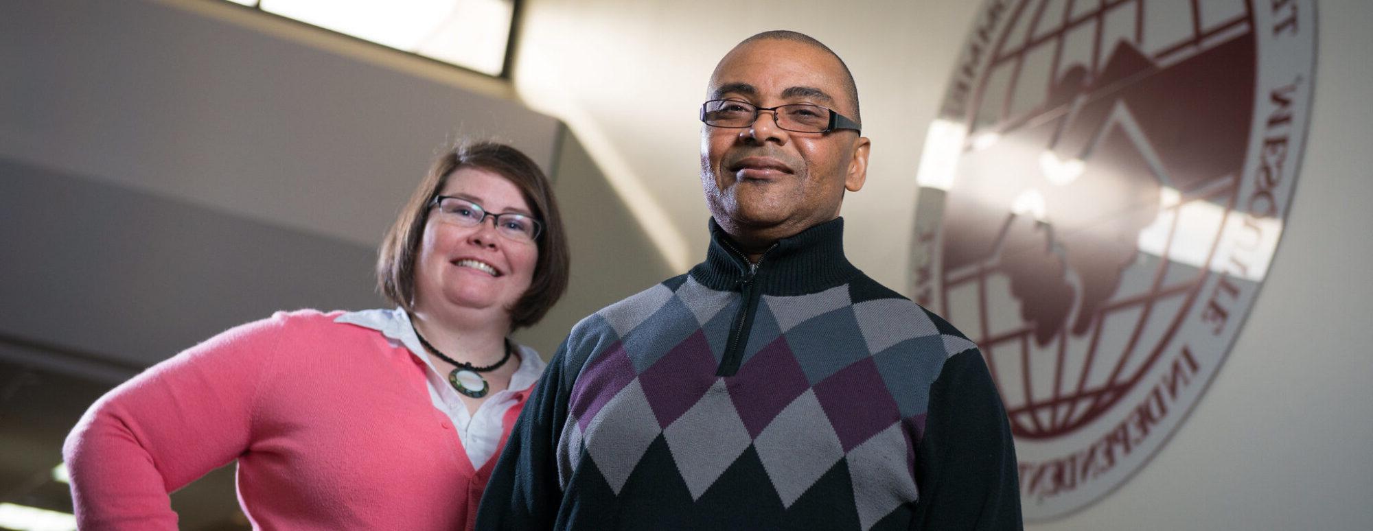 Two people standing on stairs at community college.