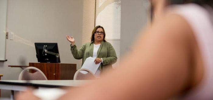 Woman holding papers and talking to students.