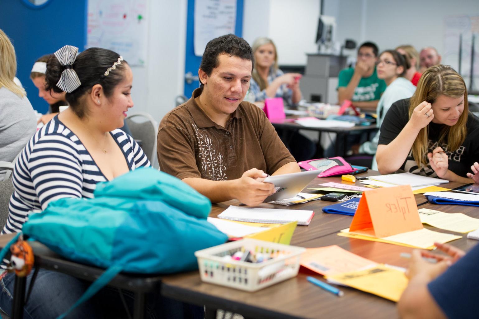 Classroom environment with adult man and woman at table with construction supplies.