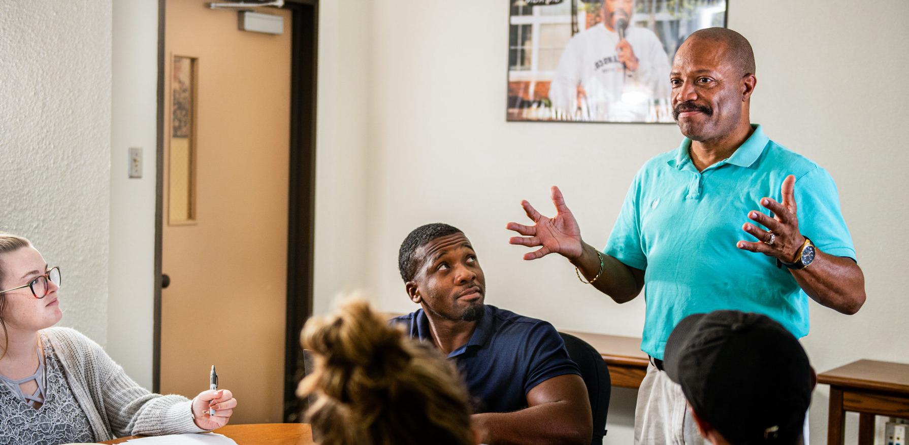 Man speaking to small group around a conference table.