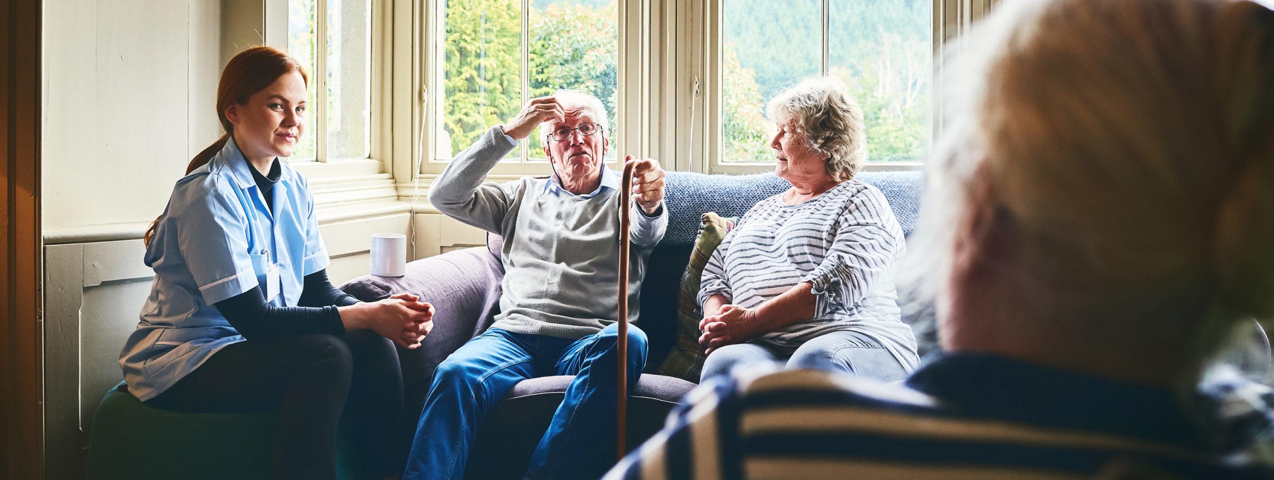 Female community nurse visiting senior people at care home.