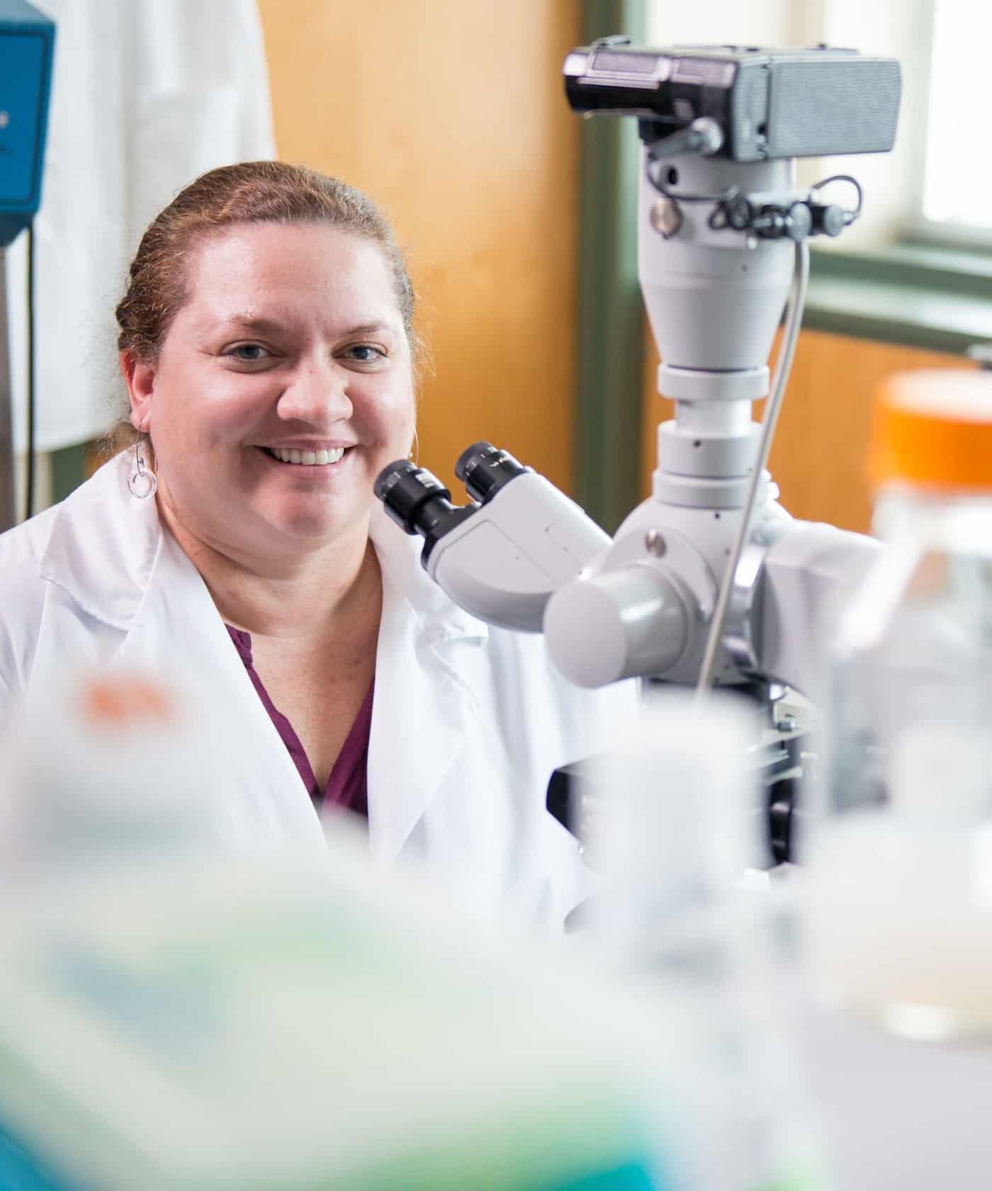 Biologist sitting next to microscope