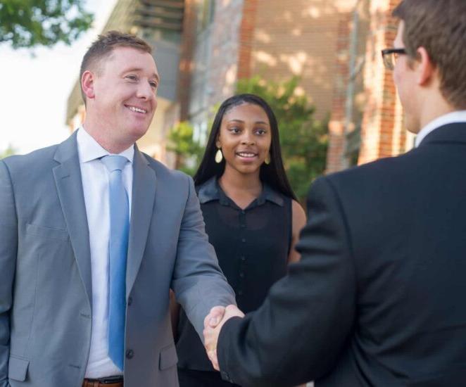 Business dressed group engaged in handshake.