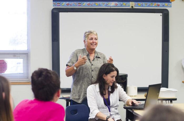 Teacher instructing a group in a classroom.