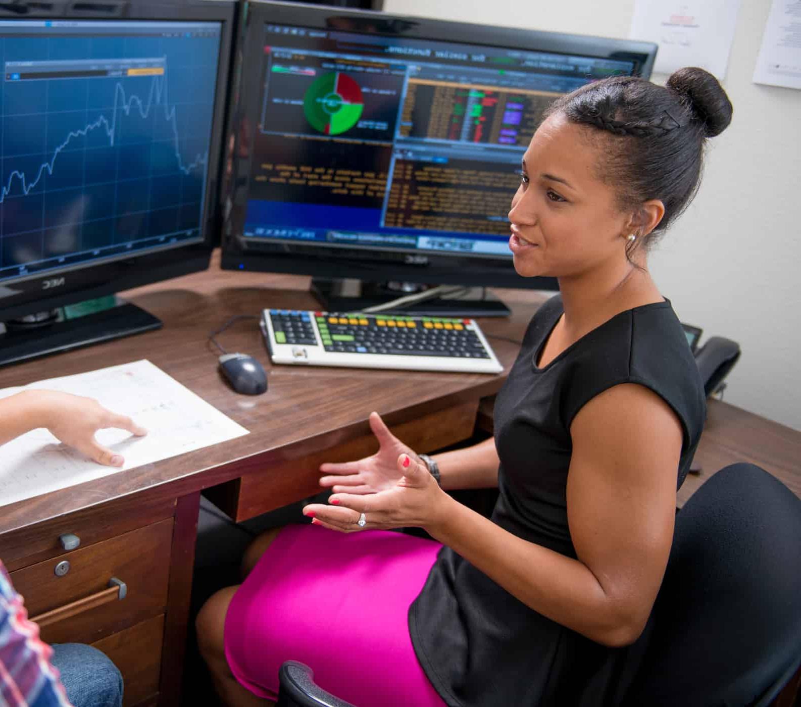 Student talking in front of computer monitors