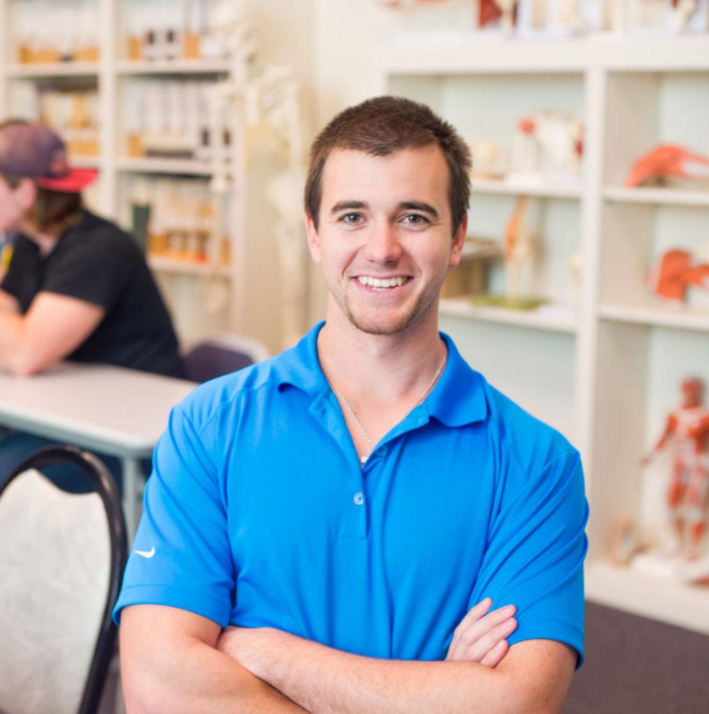 Health Human Performance student smiling at the camera with arm crossed.