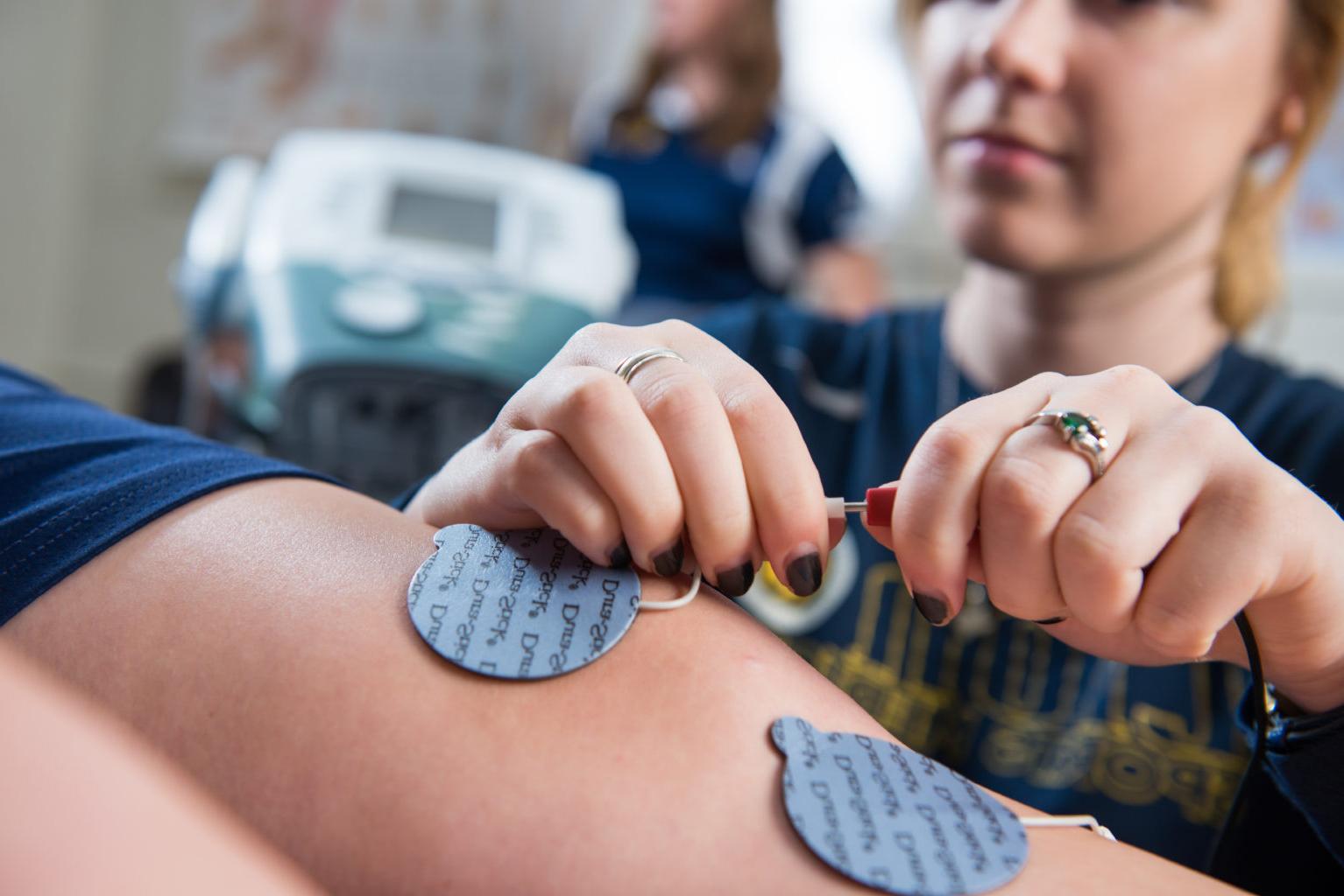 Woman putting electrodes on an athletes legs