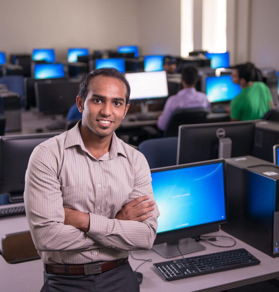 Man standing in front of a computer in a lab.