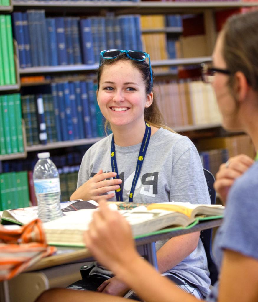 Two girls in the library studying their textbooks.