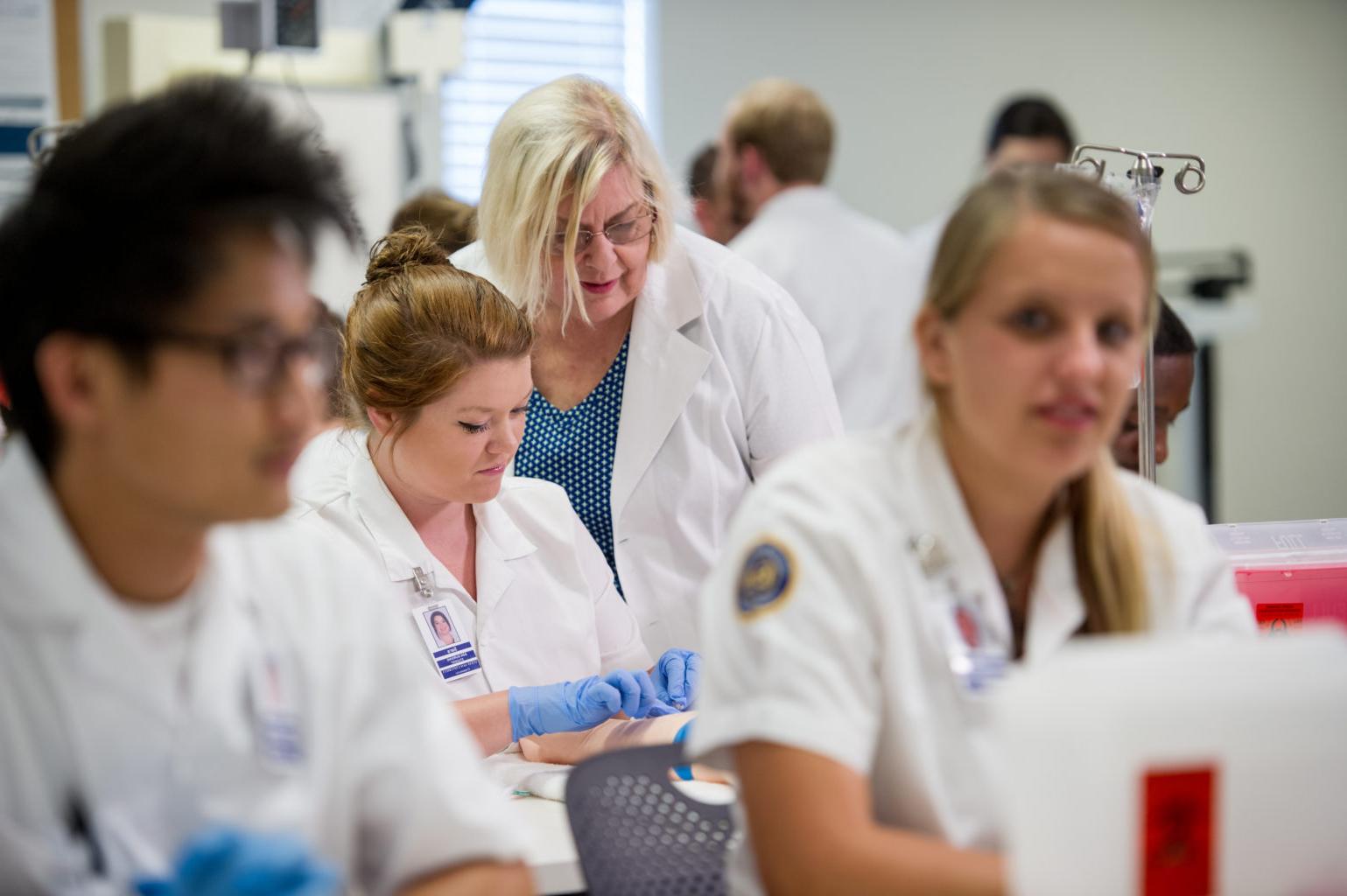 Female nursing instructor helping female nursing students