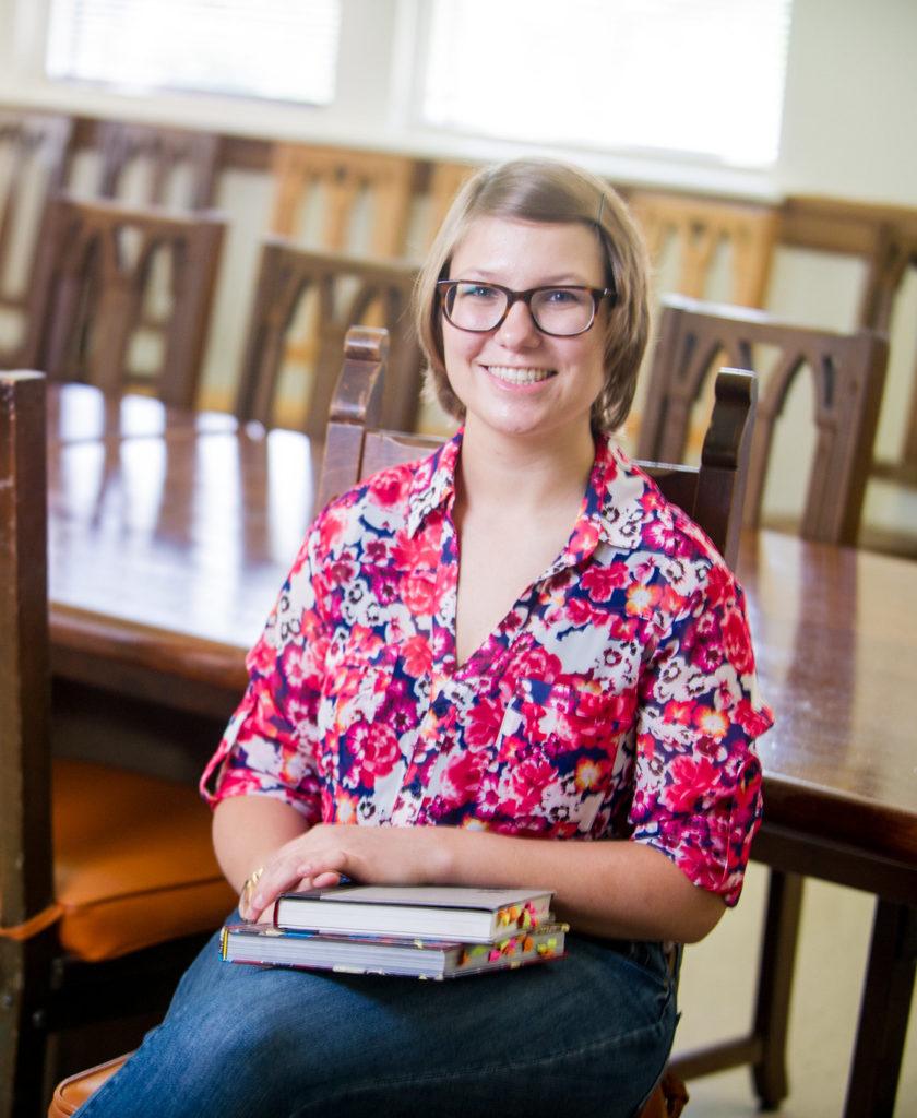 Girl sitting in chair with books in her lap.