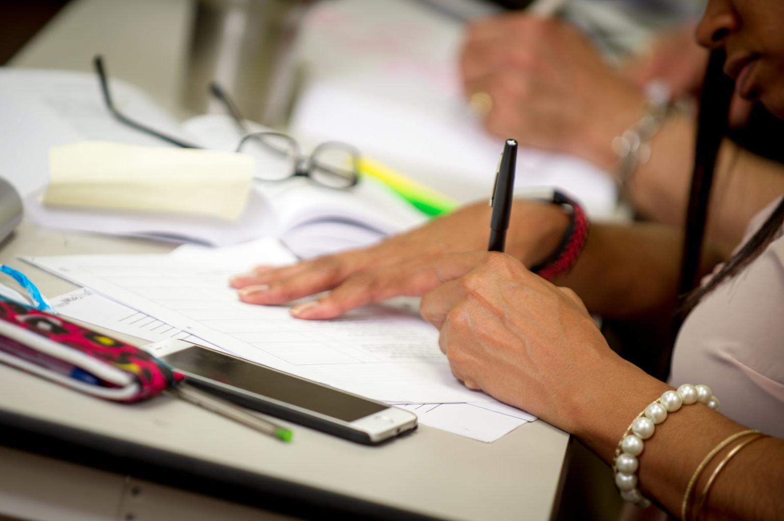 Woman's hands writing at a desk.