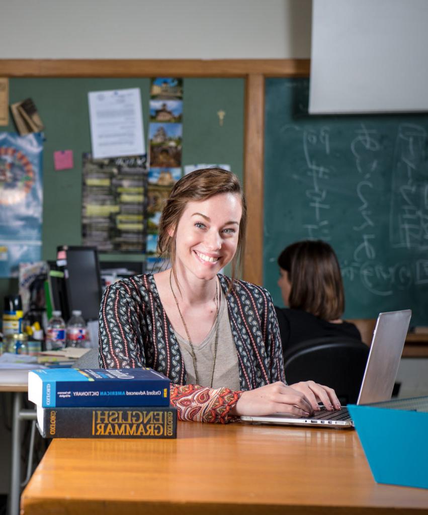 Girl in classroom with textbooks and a laptop.