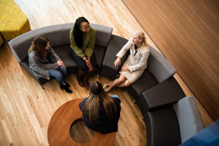 A teacher talking to a small group of student in the common area in the new health sciences building.