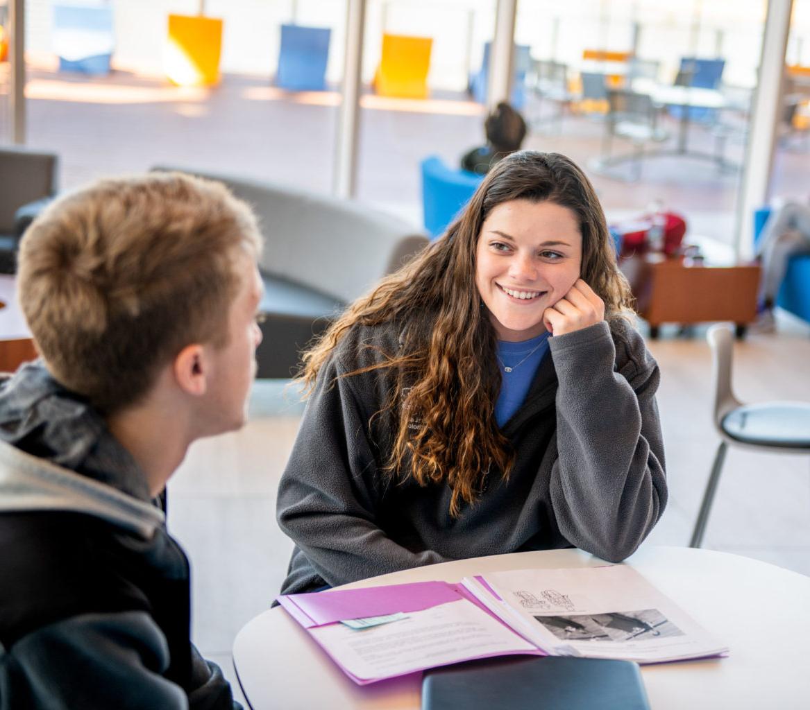 Young woman speaking with man in classroom environment