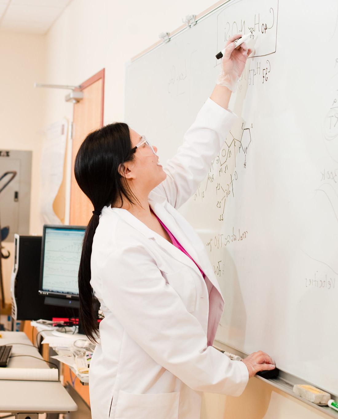 Nursing students solving a problem on a white board.