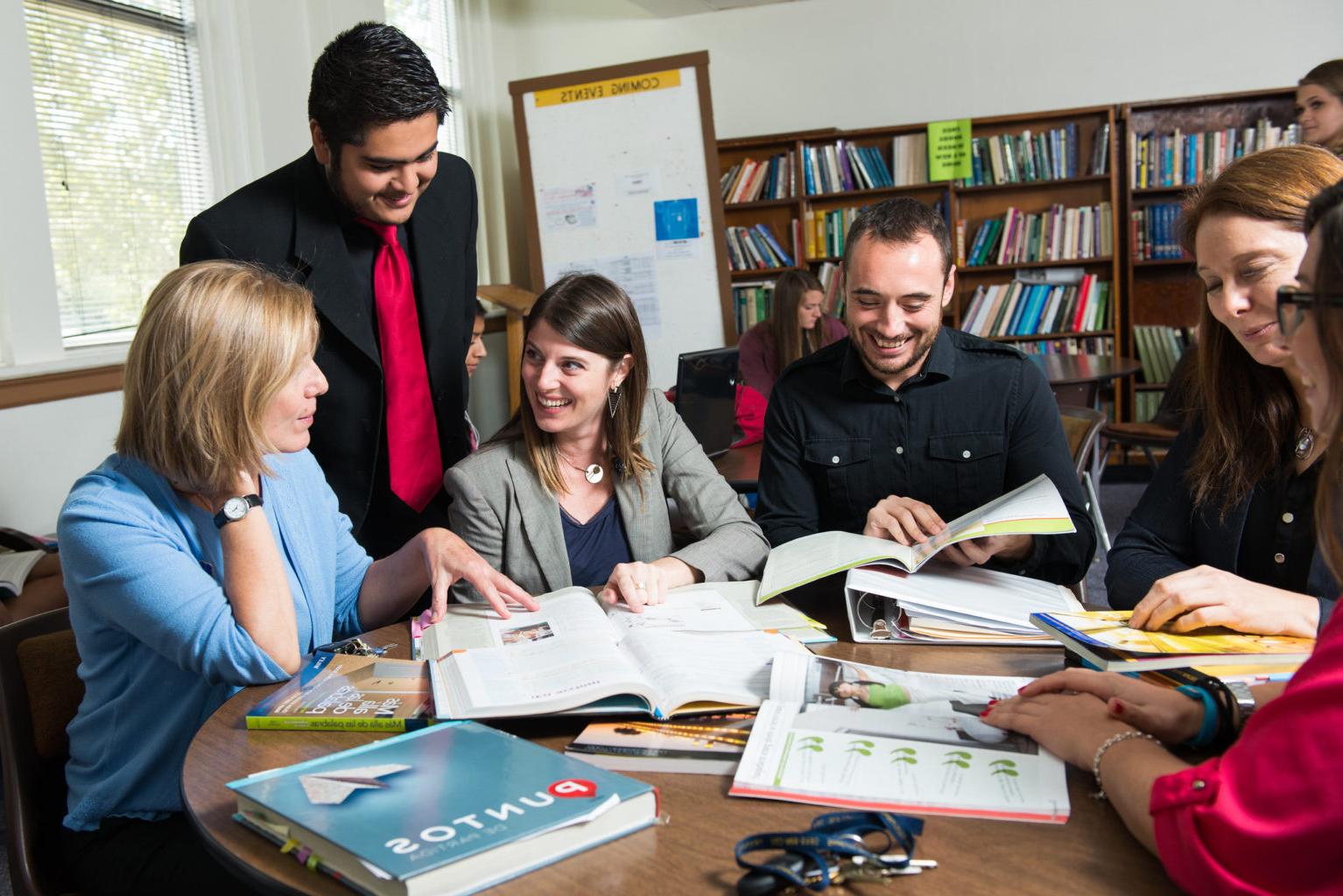 group of graduate students gathered around a table with spanish book labeled Puntos.