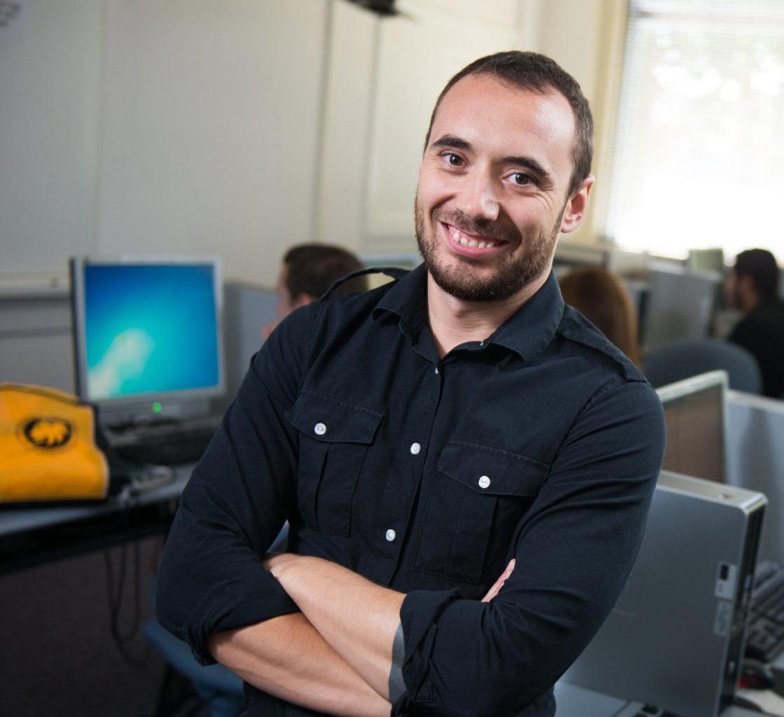 Hispanic man standing in computer lab.