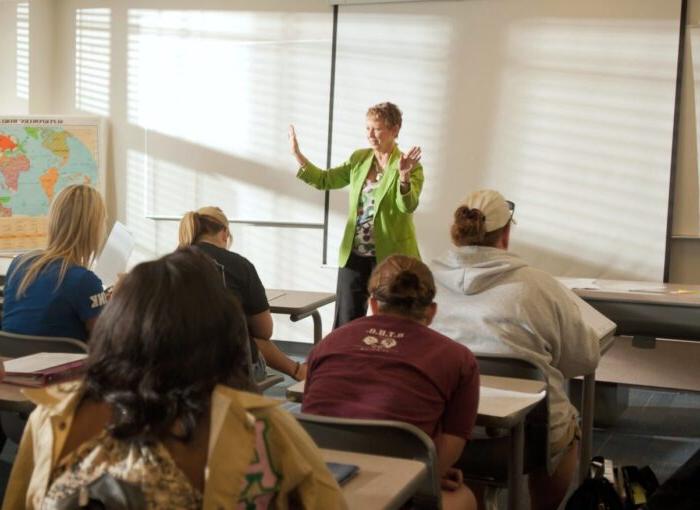 Female teacher instructing college students in classroom.