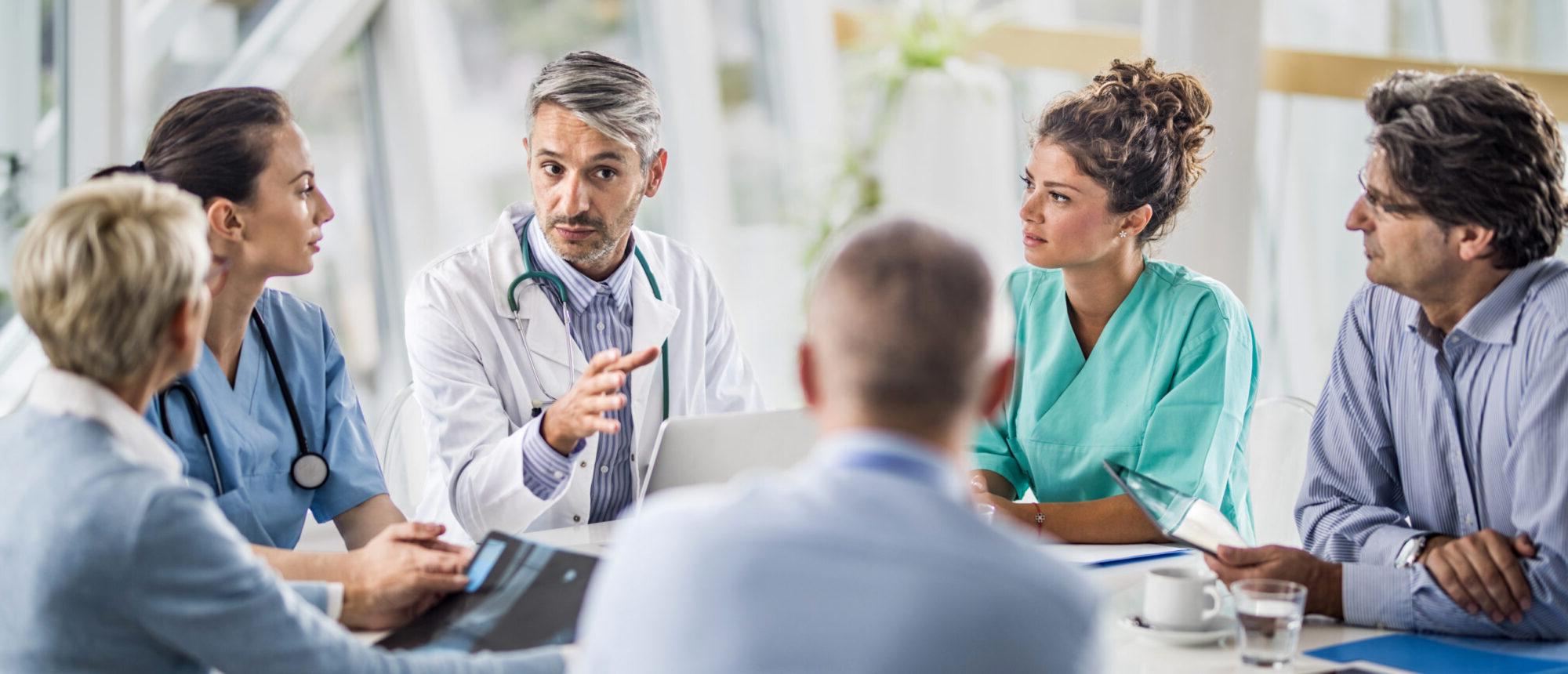 Doctor and his colleagues talking to team of business people on a meeting in the hospital.