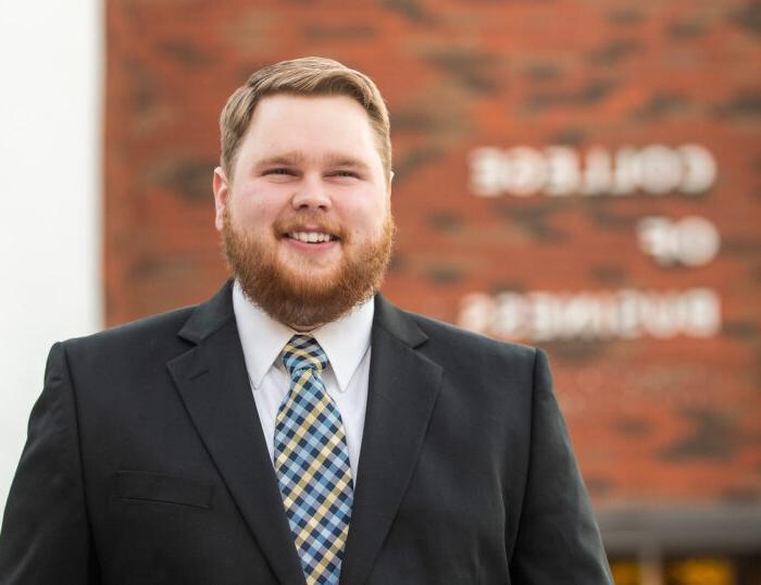 A gentlman by the name Chase Miller standing in front of the College of Business.