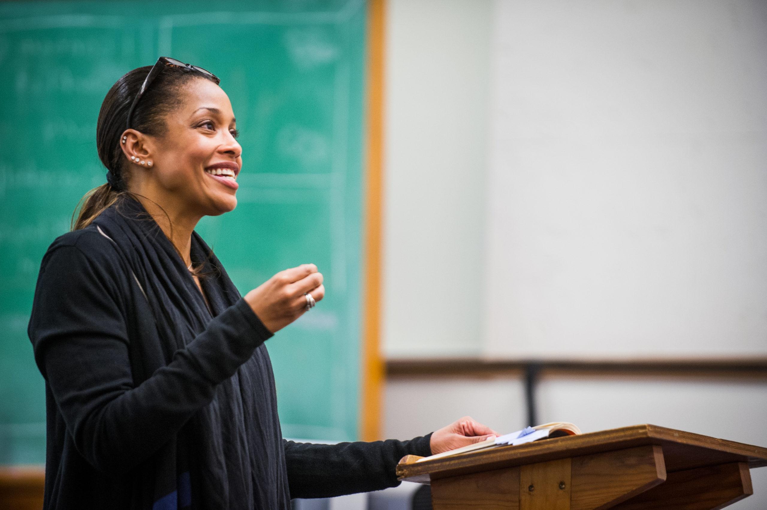 A female educator with big smile reading a poem to audience.