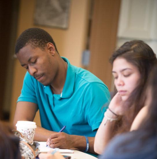 A male and female writing at a table.