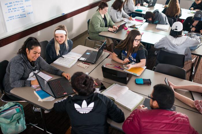 Many students in a classroom working together and talking.