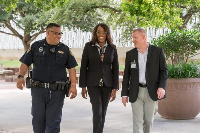 Three professionals walking, smiling, and talking to each other.