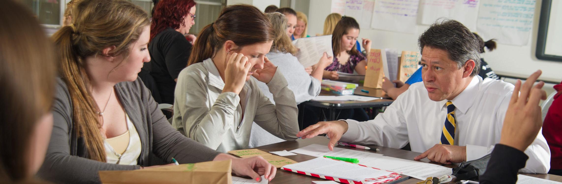 Instructor sitting at table with students.