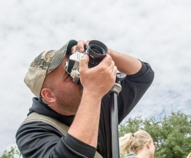 man shooting photos with an older man and woman in the background.