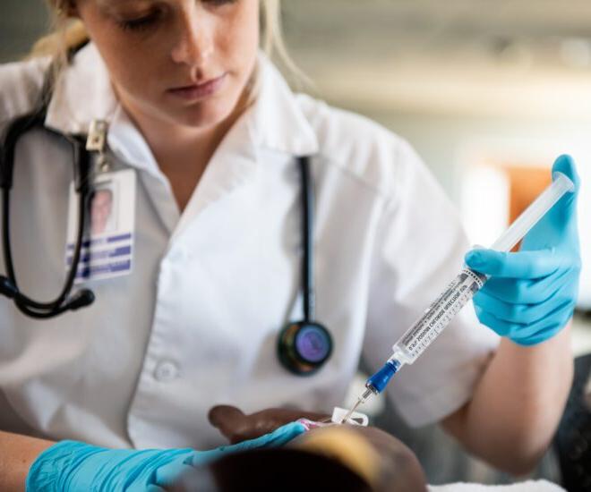 A Female student practicing to give an injection on a mannequin.