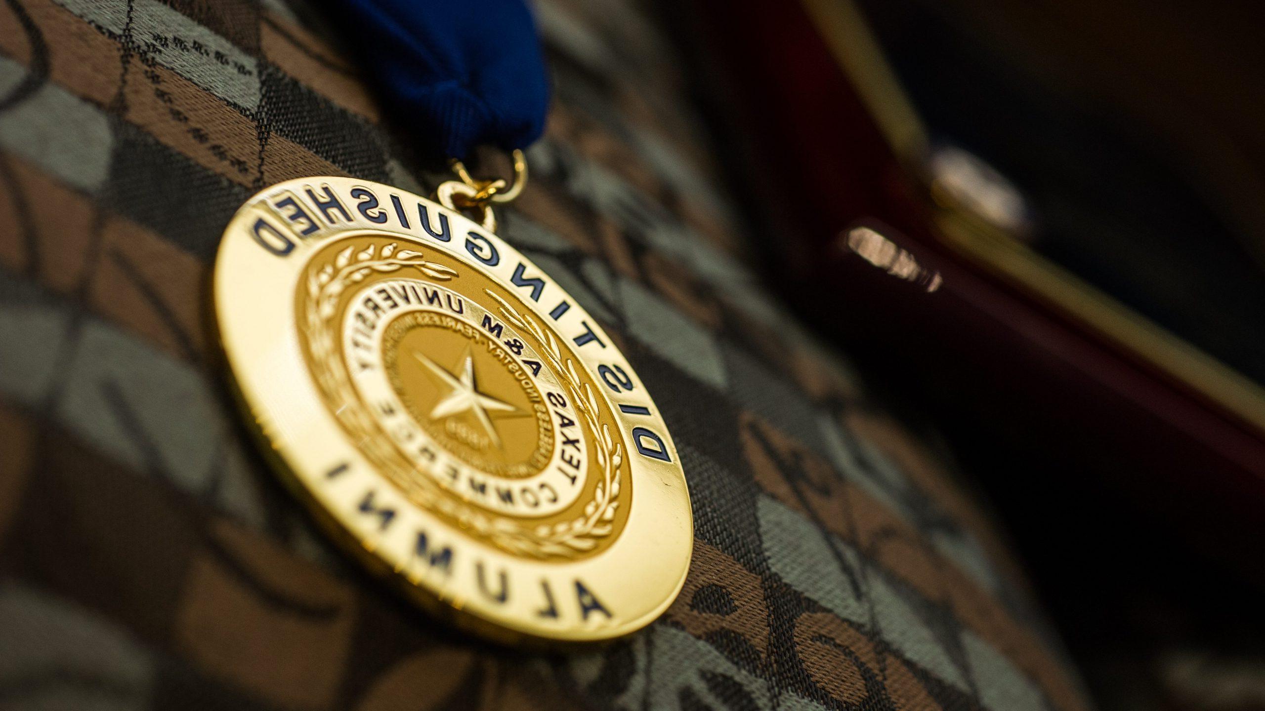 A golden badge with distinguished alumni.