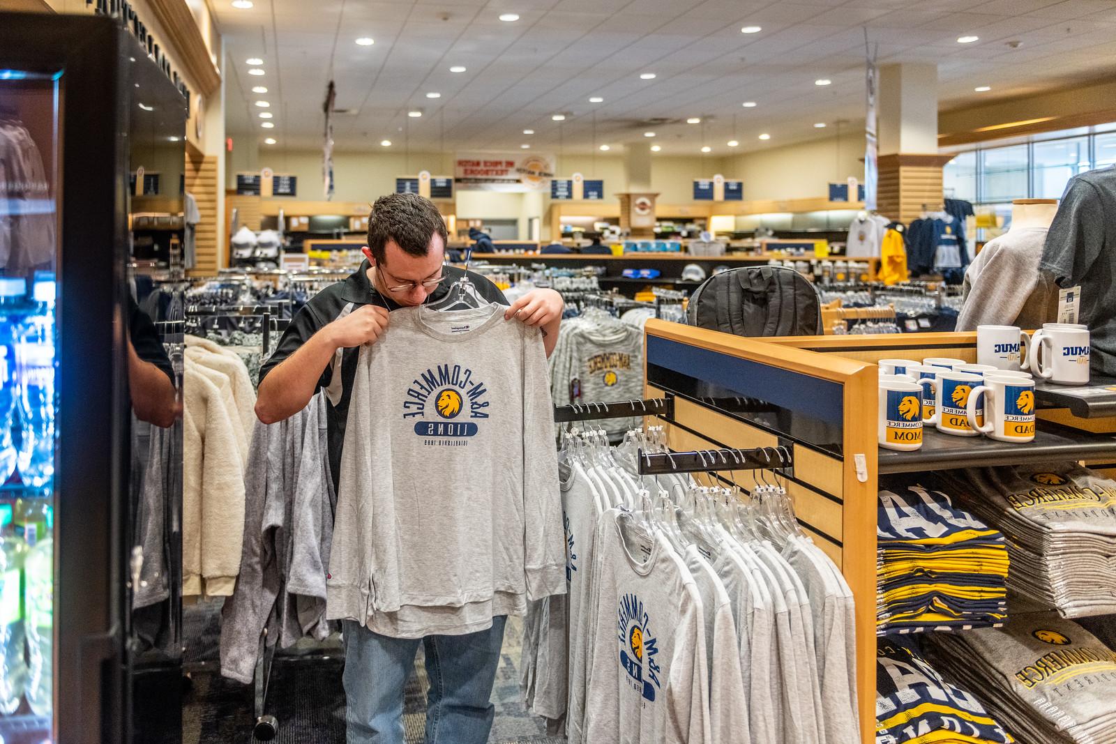 A male looking at a lions shirt at the bookstore.