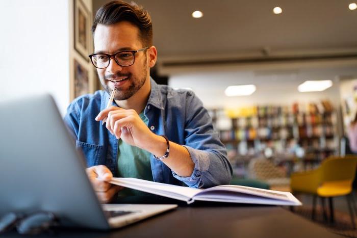 Smiling male student working and learning in a library