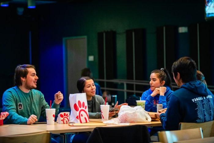 A group of student sitting in a place where they can eat and on the table is chick fila.