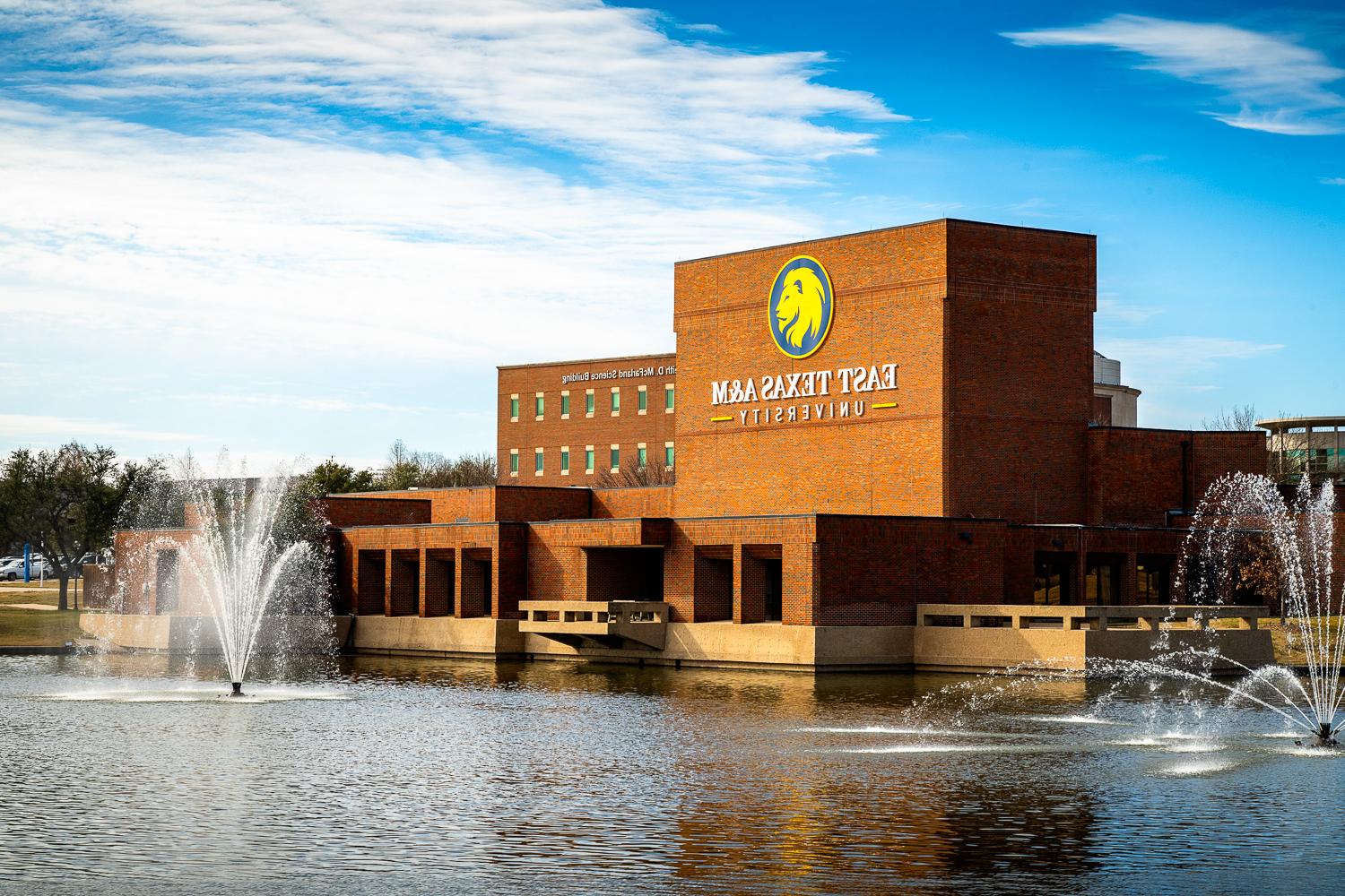 Performing Arts Center of East Texas A&M University with fountains and a clear blue sky.